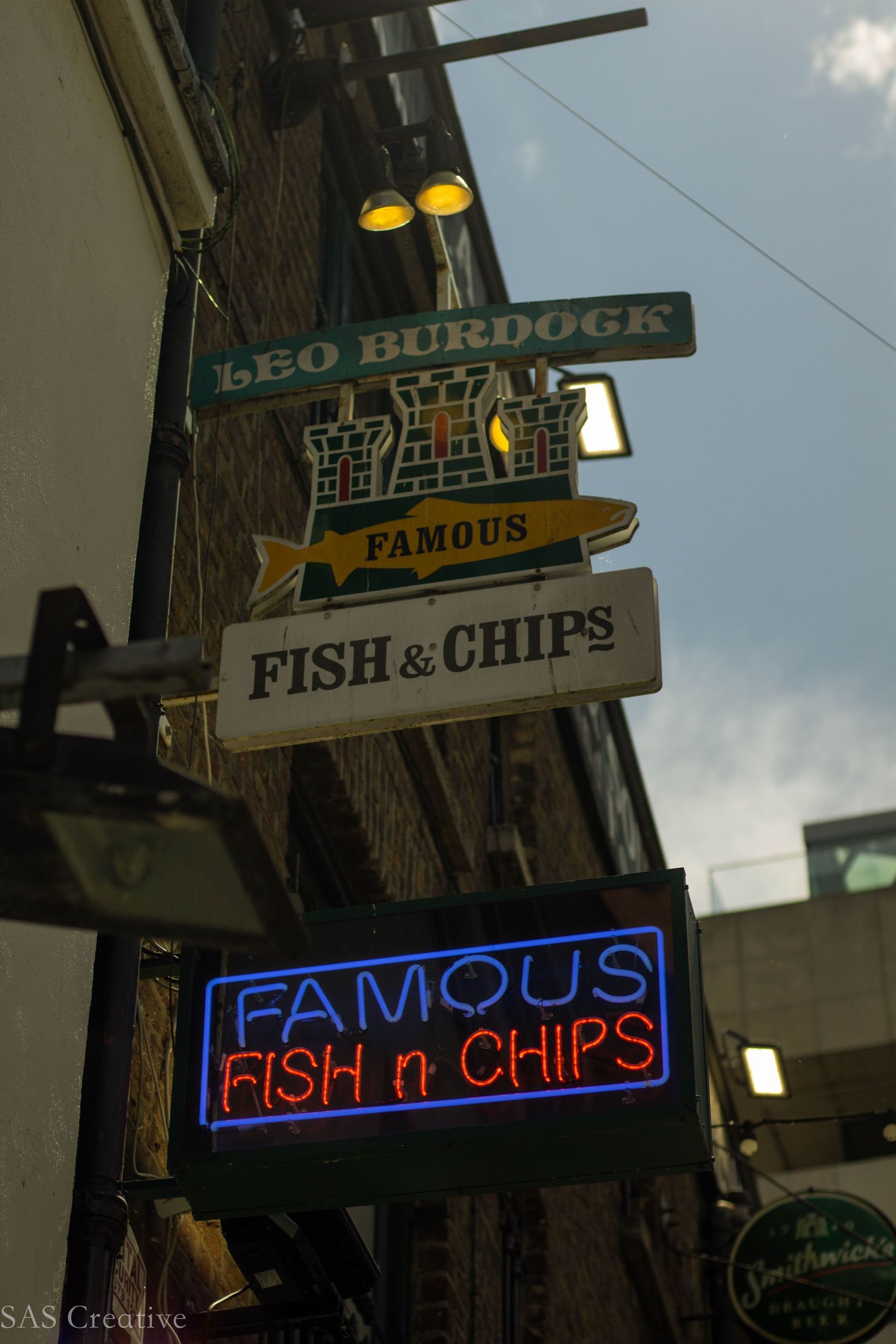 Neon and painted signs for Leo Burdock Famous Fish and Chips restaurant on a brick building in Dublin.