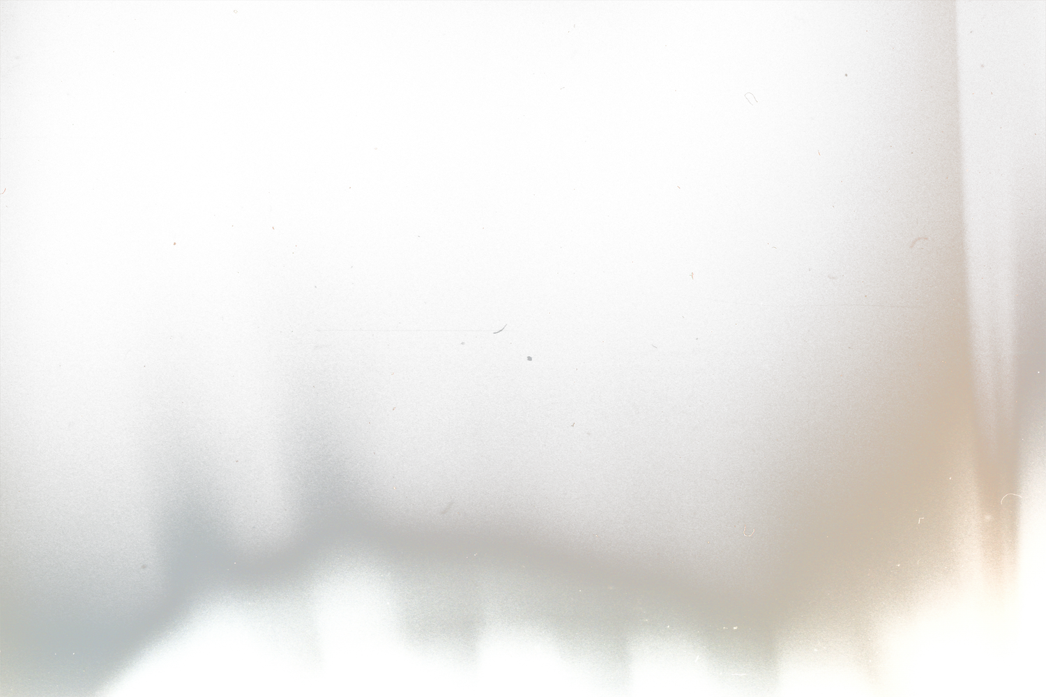 A soft, blurred white background with subtle shadows and warm tones creating an abstract minimalist texture.