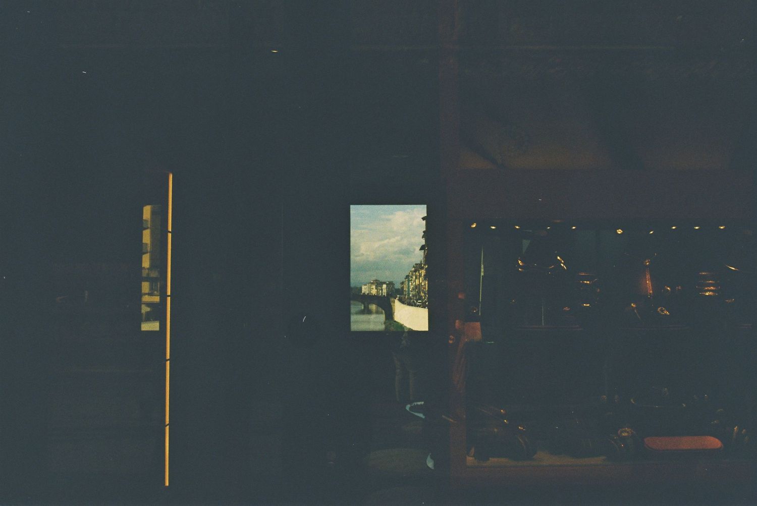 Dark interior room with a small window revealing a bright cityscape outside.