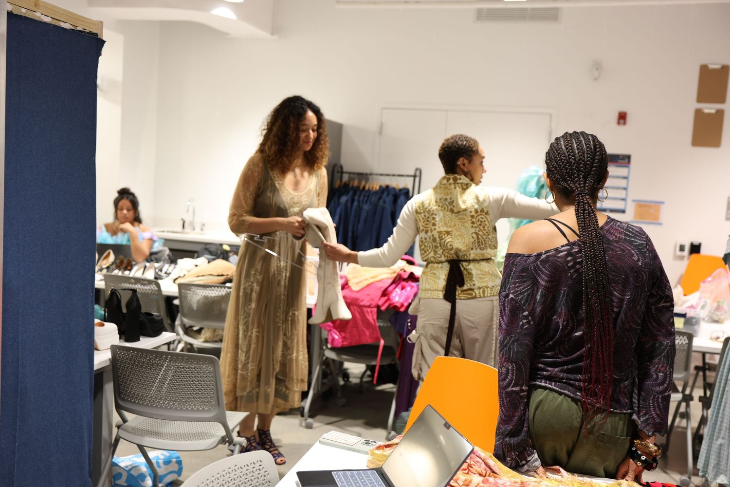 Fashion students collaborate in a design studio surrounded by colorful fabrics and sewing equipment.