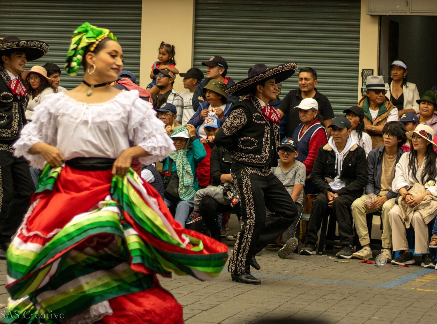 Traditional Mexican folkloric dancers in colorful costumes performing at a street festival.