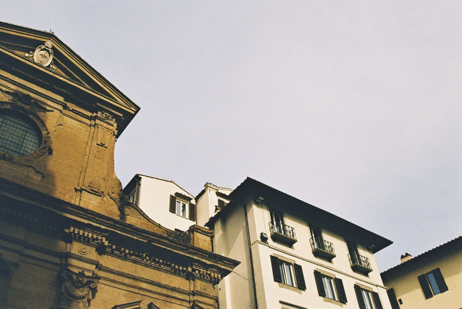 Low angle view of historic Florentine church and apartment buildings against overcast sky.