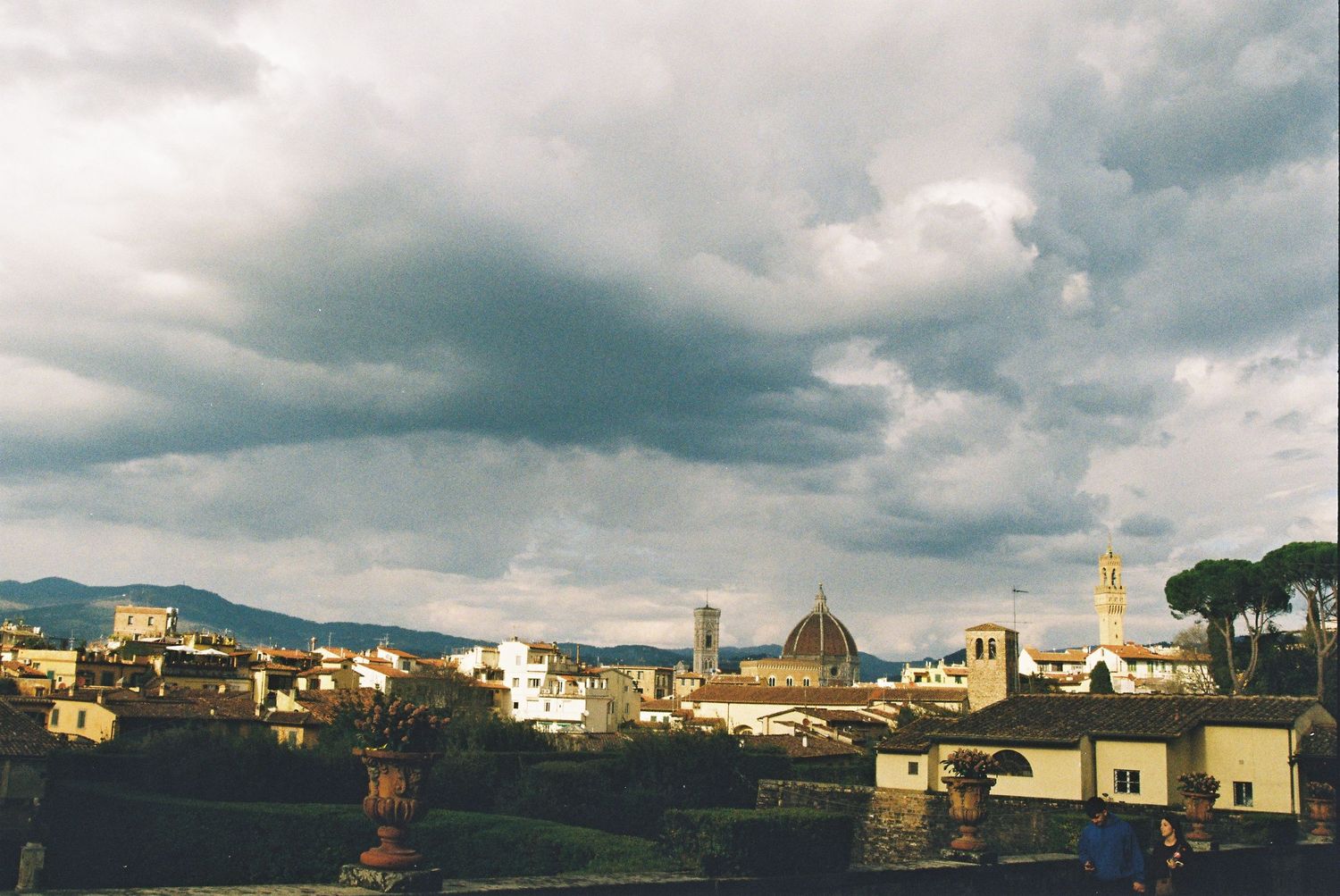 Panoramic view of Florence skyline featuring the iconic Duomo cathedral dome under dramatic stormy clouds.
