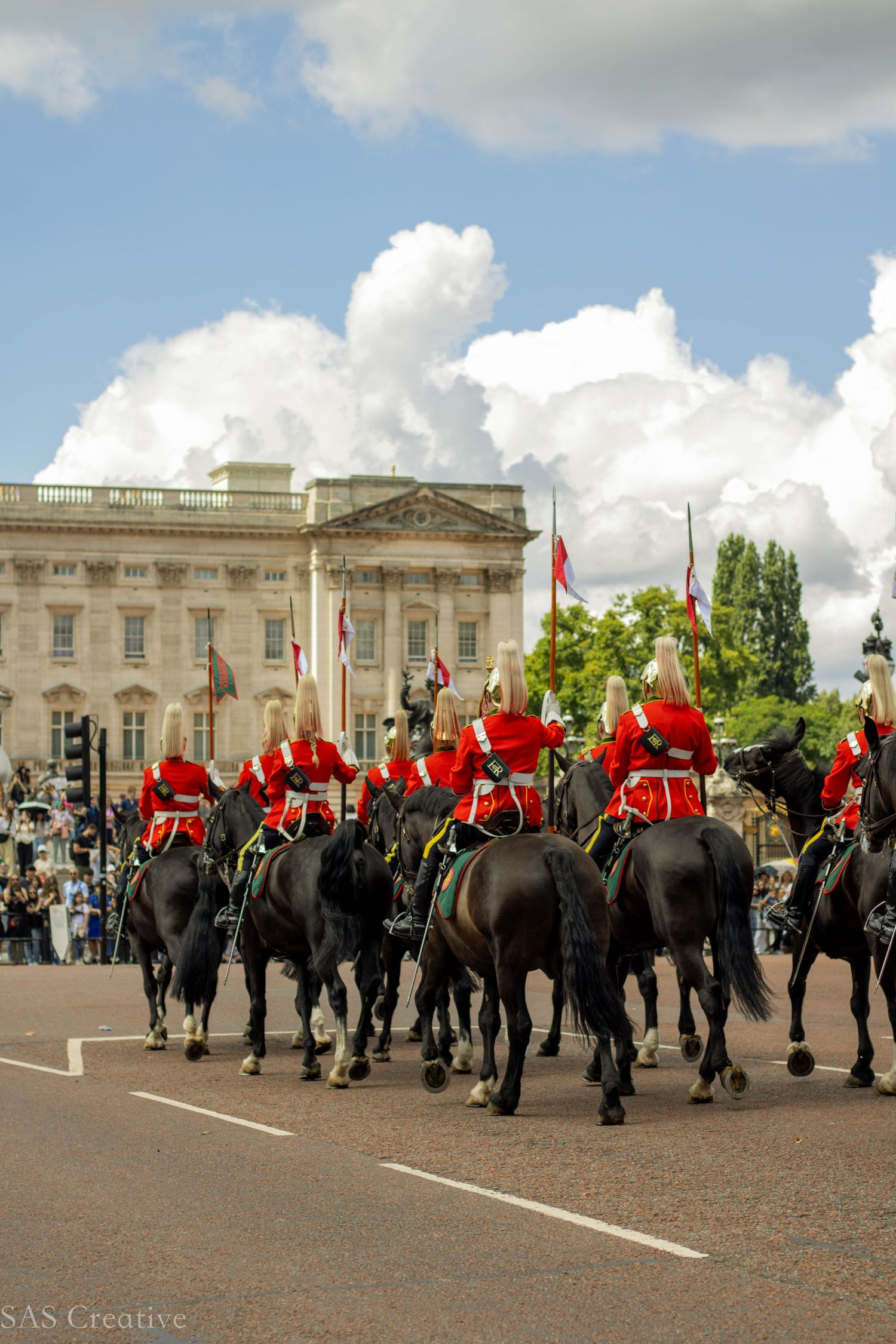 Royal Horse Guards in red uniforms riding black horses past Buckingham Palace London.