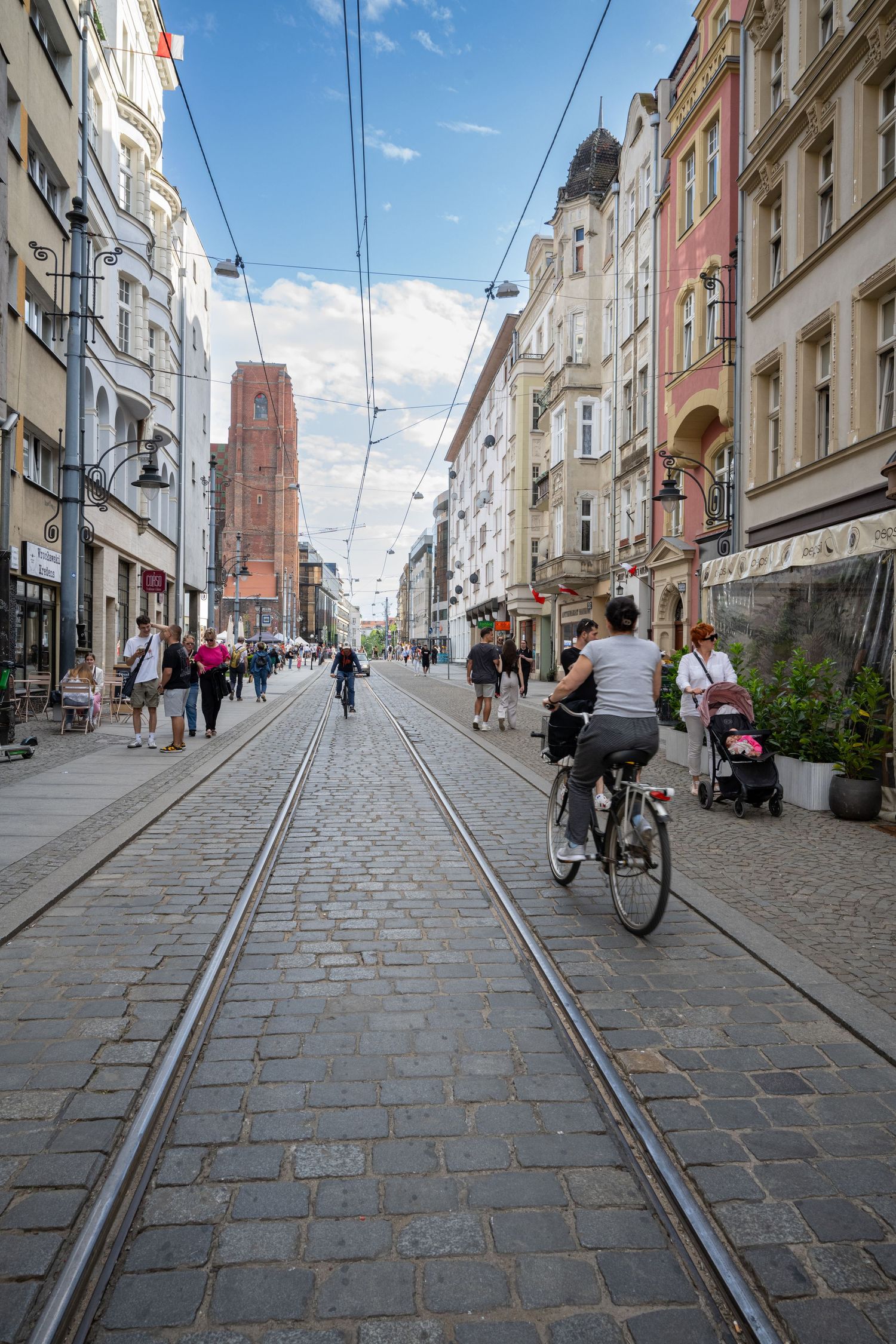 Historic cobblestone street with tram tracks and traditional buildings in Wroclaw's city center on a sunny day.