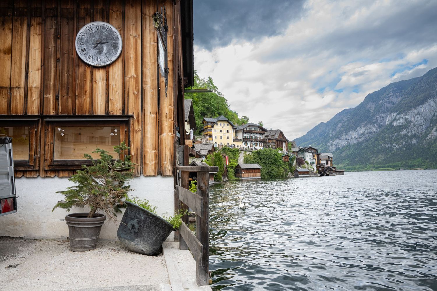 A scenic panoramic view of Lake Hallstatt in Austria with wooden boat docks and Alpine mountains in the background.