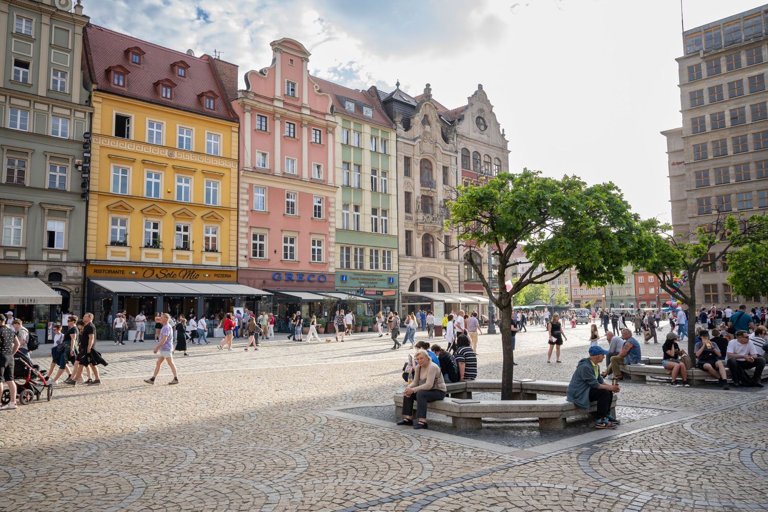 Panoramic view of colorful historic buildings and cobblestone square in European old town marketplace.