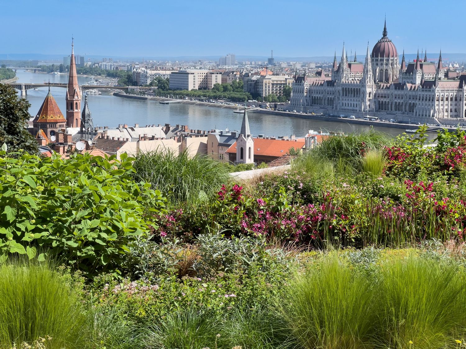 Panoramic view of Budapest's skyline with the Parliament building and Danube River on a sunny day.