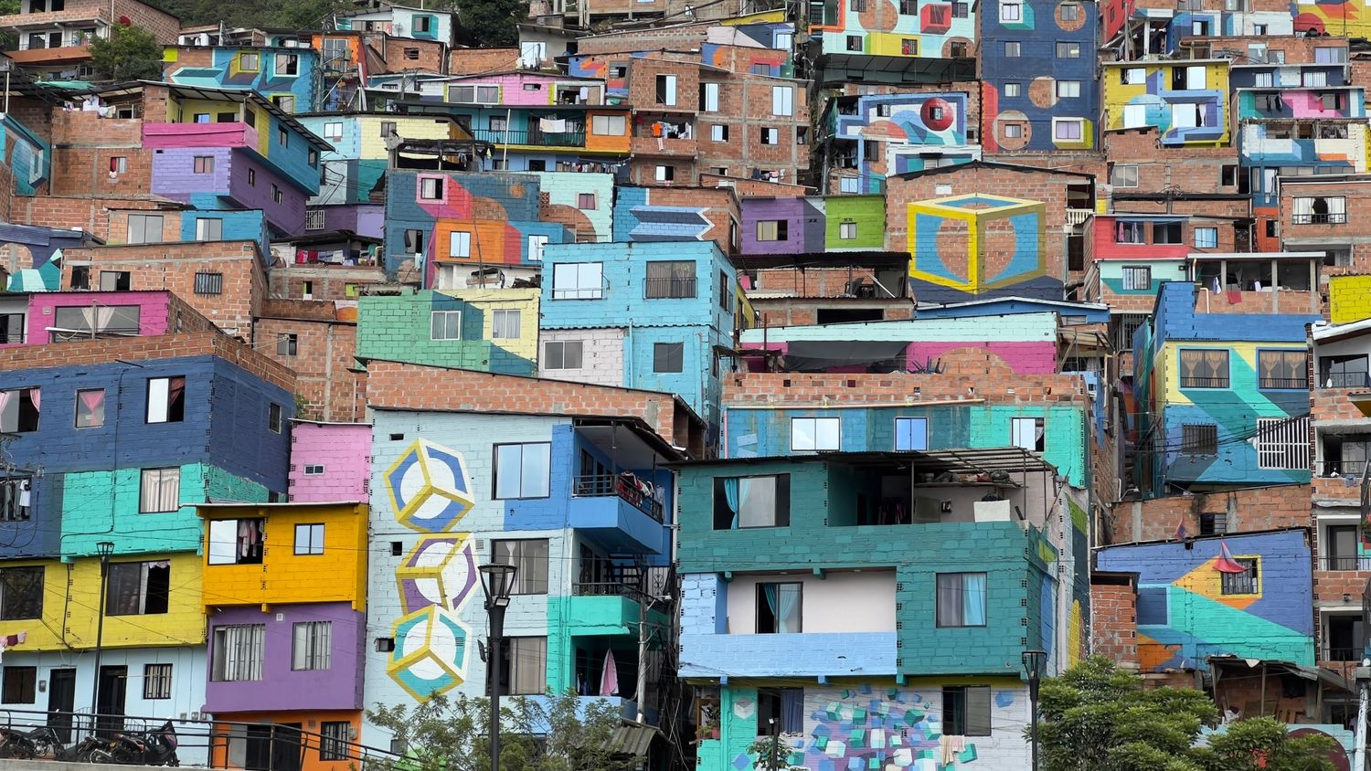 Colorful favela houses stacked on hillside in Rio de Janeiro with vibrant blue, yellow, and purple painted buildings.