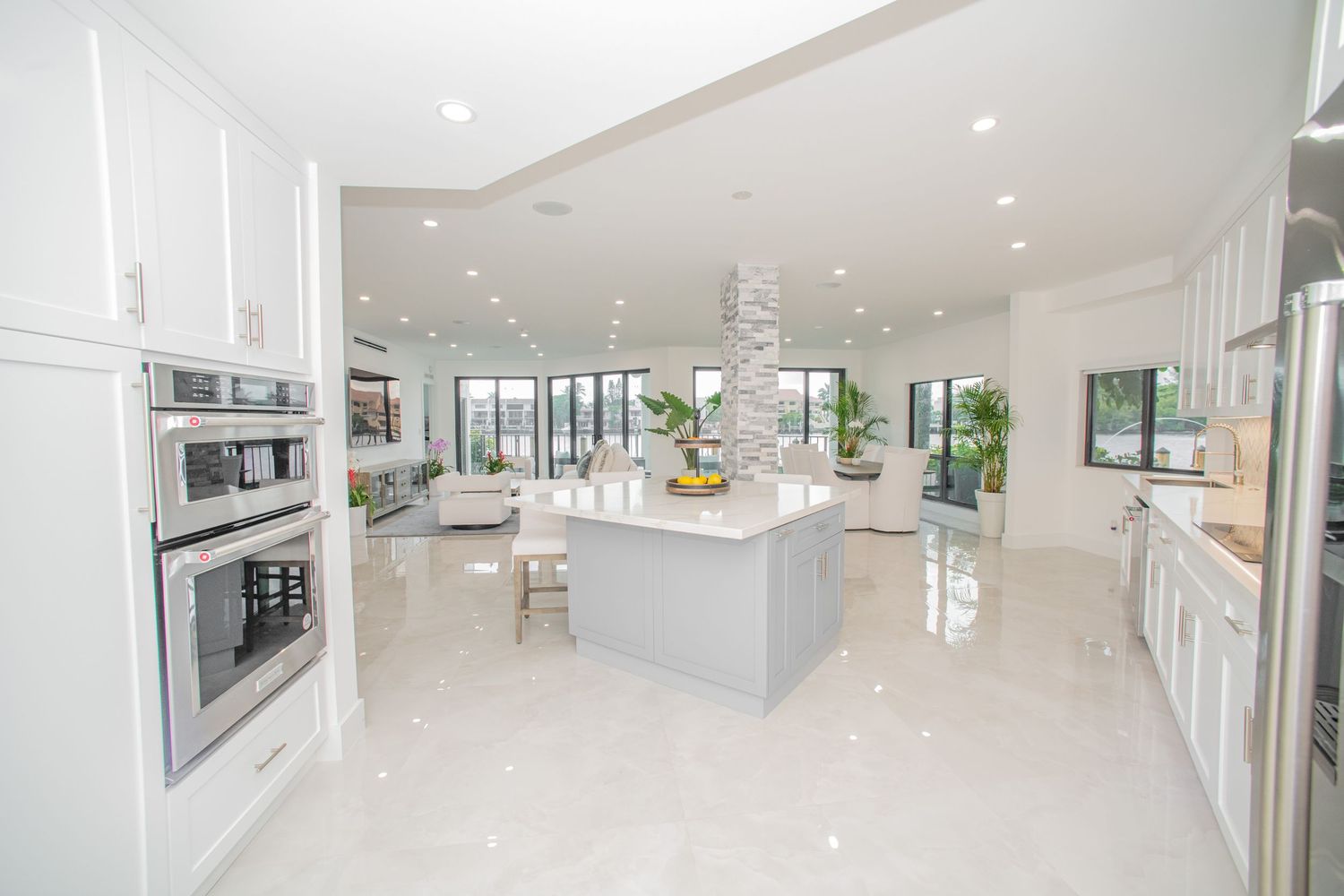 Modern white kitchen interior with sleek cabinets, quartz countertops and stainless steel appliances in open concept design.