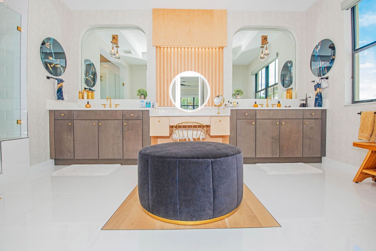 Modern bathroom interior with dark blue velvet ottoman and white cabinets in luxury home.