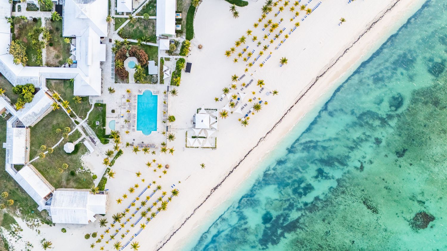 Aerial view of luxury overwater bungalows with turquoise lagoon waters and wooden walkways in tropical paradise.
