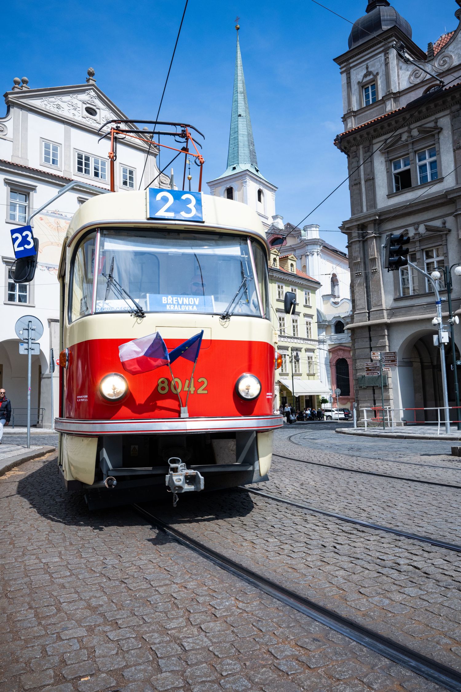 Six sequential photos show a red and white tram moving along cobblestone tracks through a historic European city street.