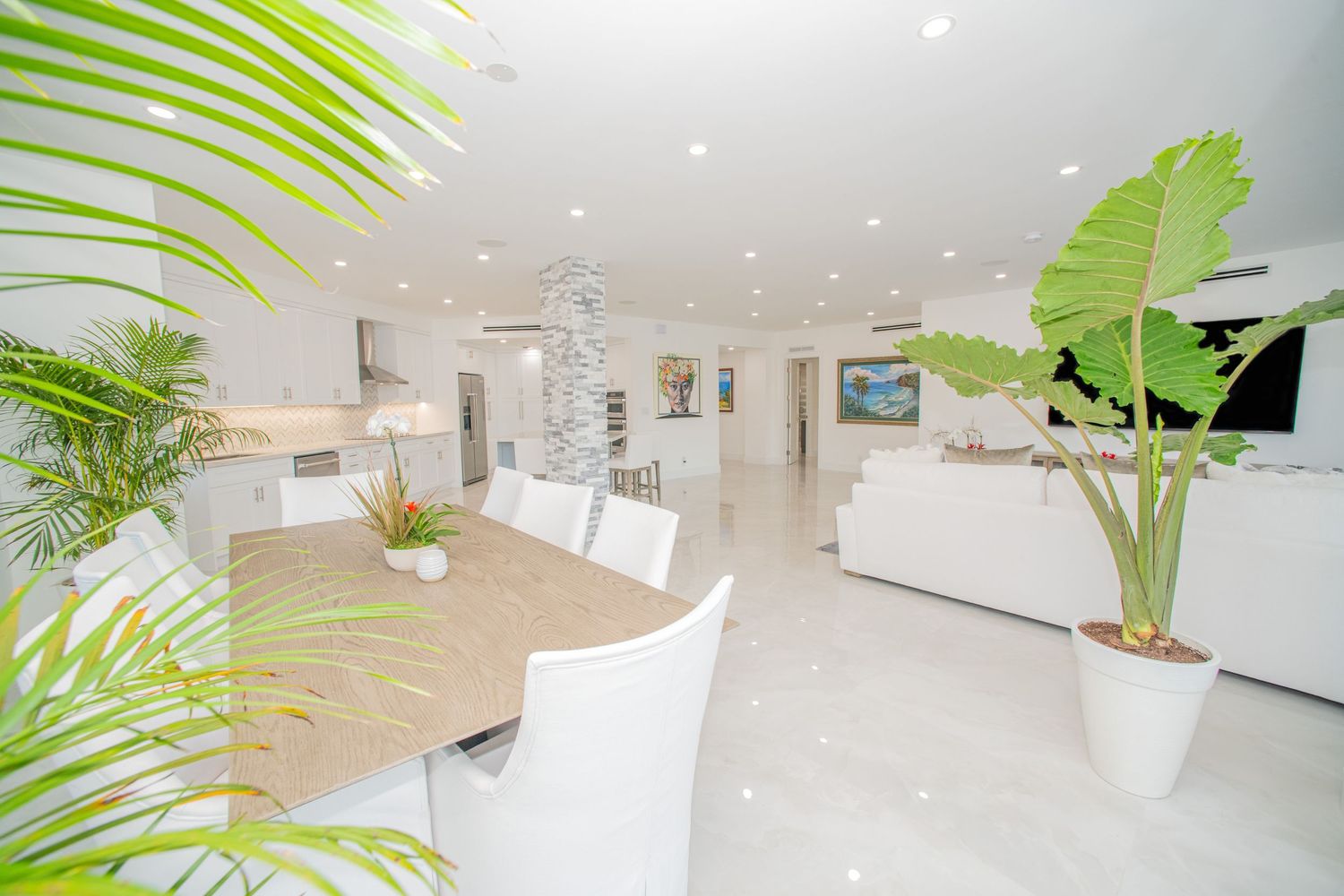 Modern white interior design with green palm plants and natural light creating a bright, minimalist aesthetic.