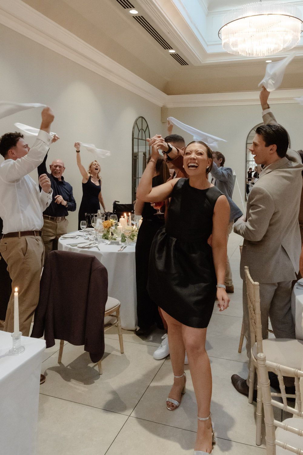 Wedding guests waving napkins as bride and groom enter the reception room.