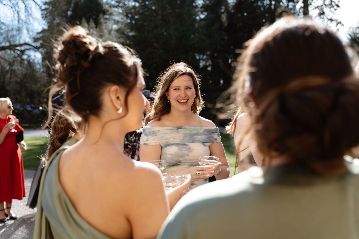 Bride smiling and socializing with guests during outdoor wedding cocktail reception.