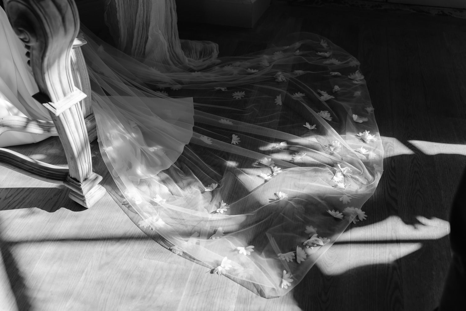 Black and white artistic close-up of a bridal veil with floral details casting shadows in natural light.