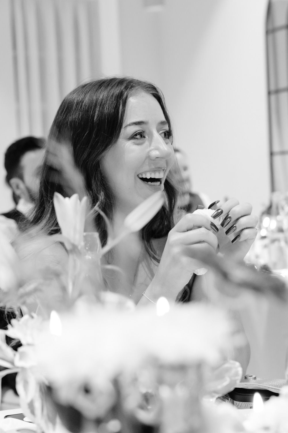 Young woman laughing with delight at a candlelit wedding reception table.