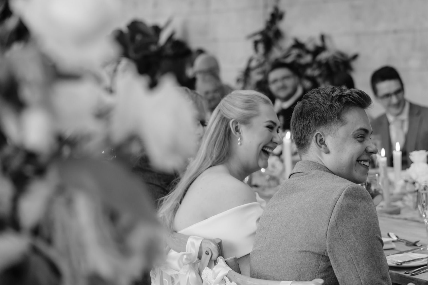 Bride and groom sharing a joyful laugh together at their wedding reception dinner table.