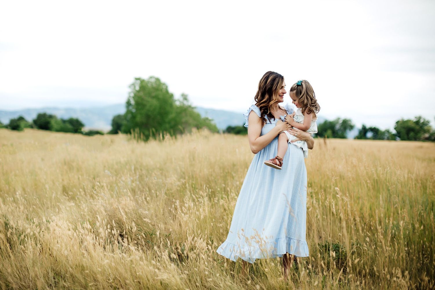 People walking through a sunlit meadow with tall golden grass on a summer day.