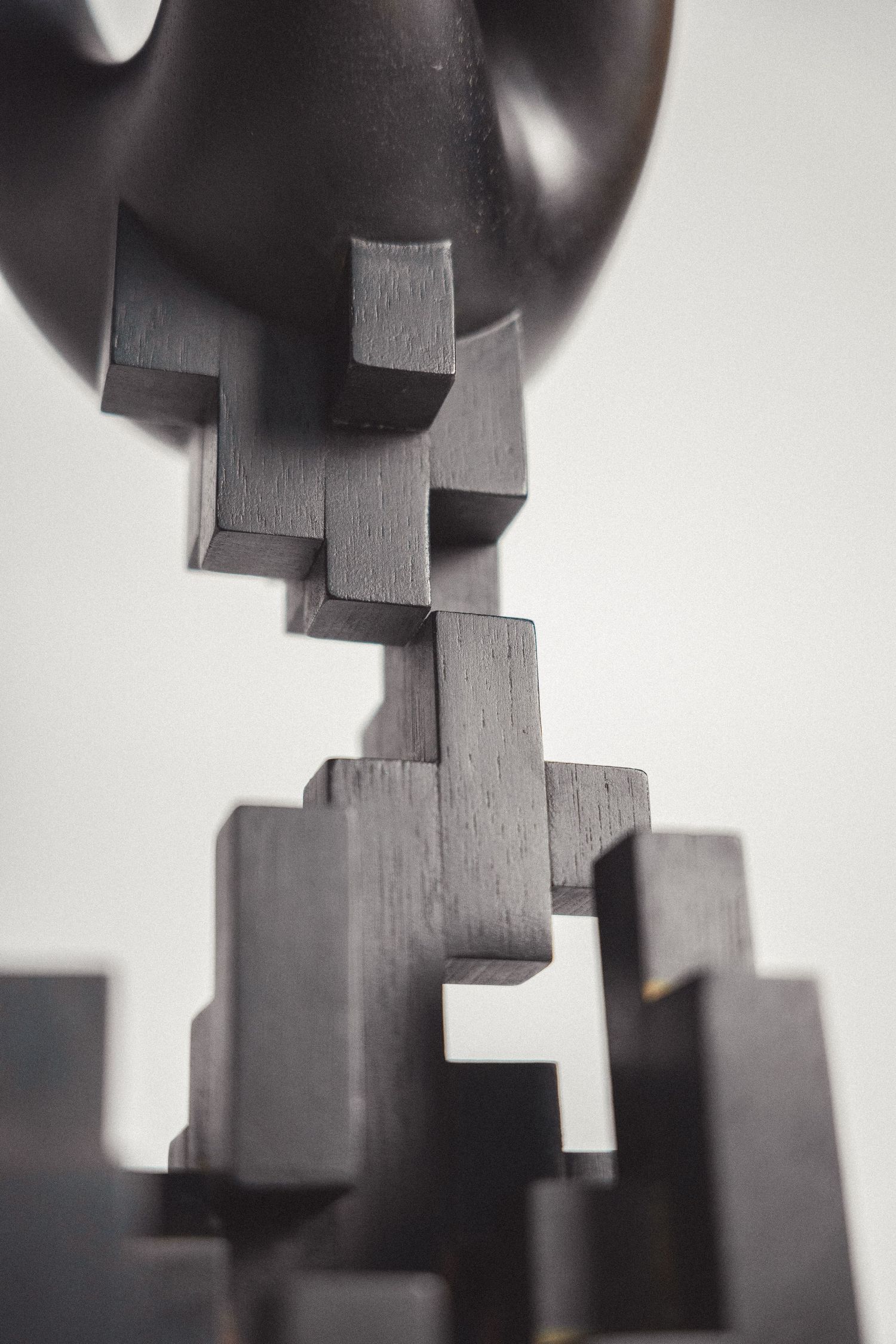 Close-up of a dark wooden geometric abstract sculpture with interlocking block forms.