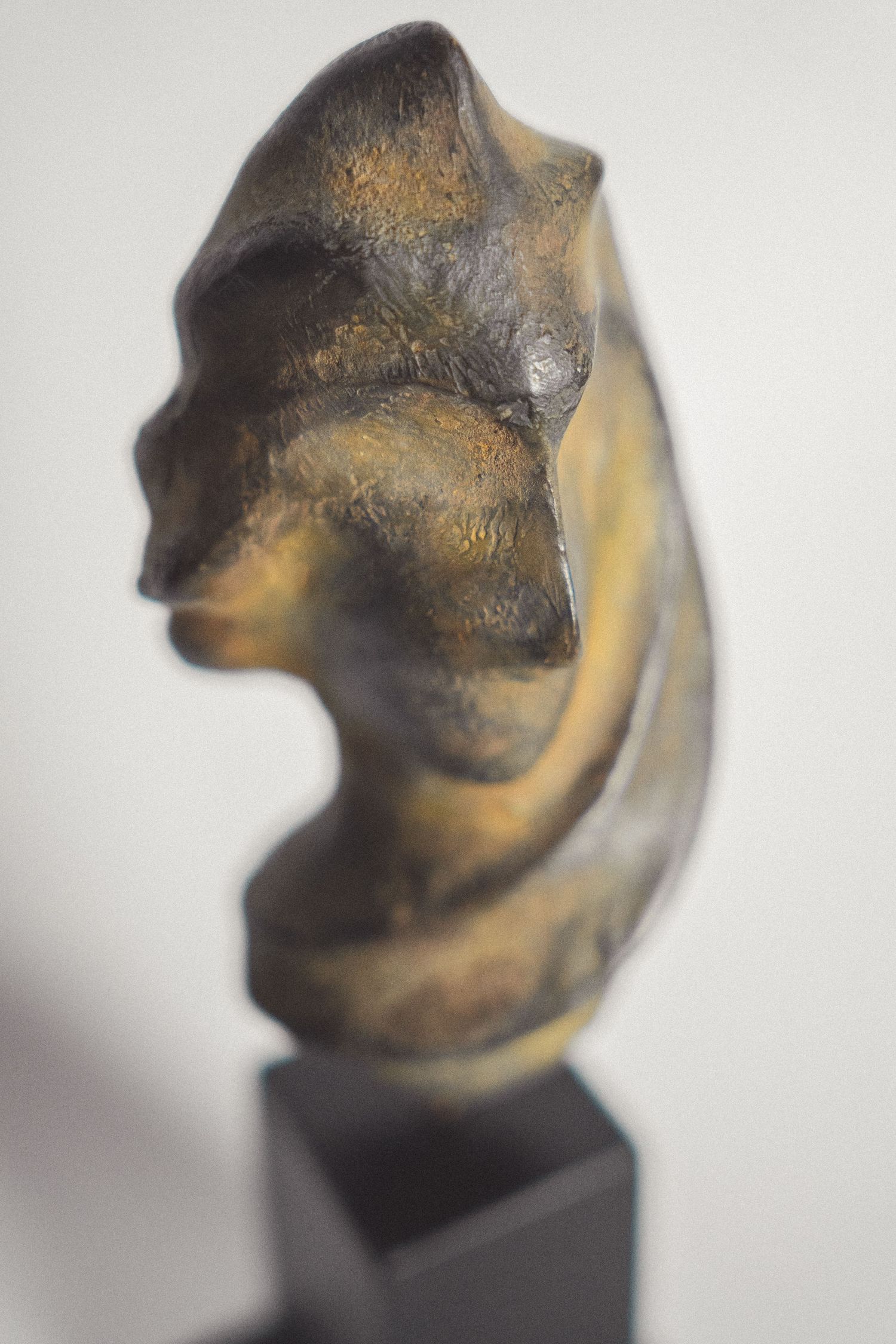 Abstract bronze sculpture of a human torso on a black pedestal, with golden-brown patina finish.