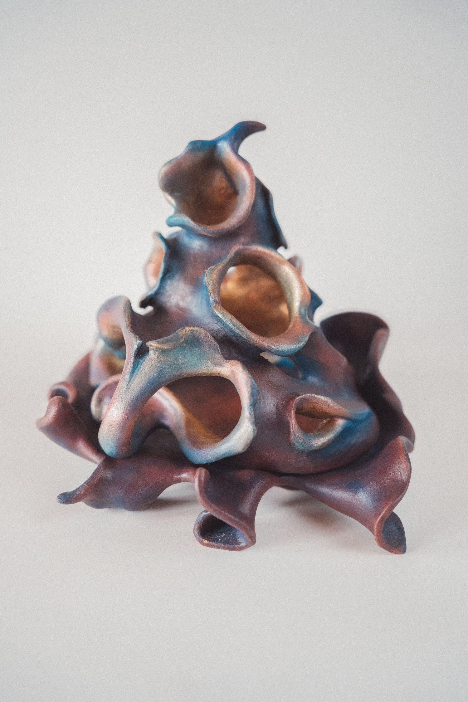 Organic ceramic sculpture with ruffled openings in purple and blue tones, resembling natural coral or sea life forms.