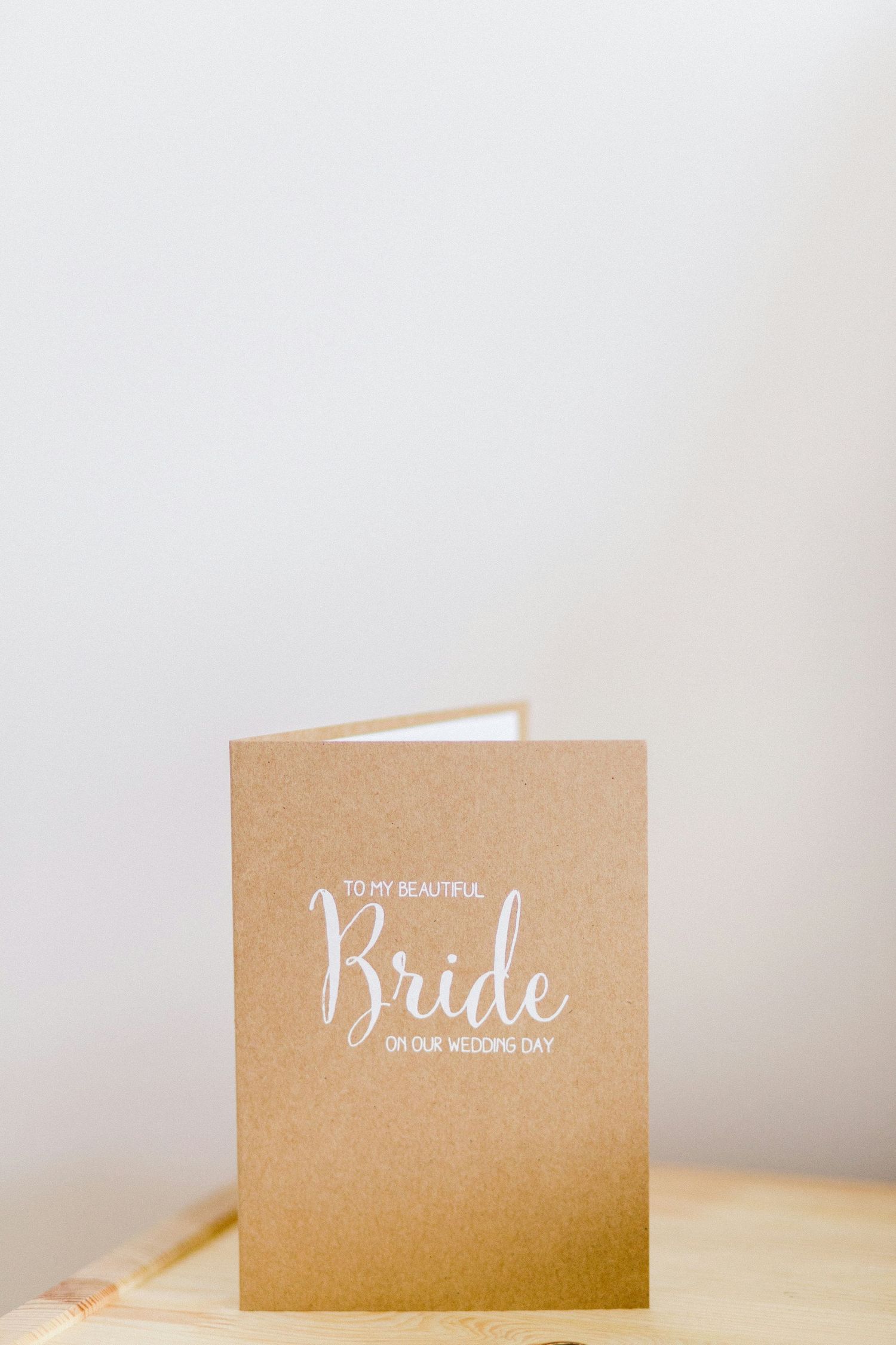 Kraft paper wedding card reading To My Beautiful Bride On Our Wedding Day on a wooden surface.