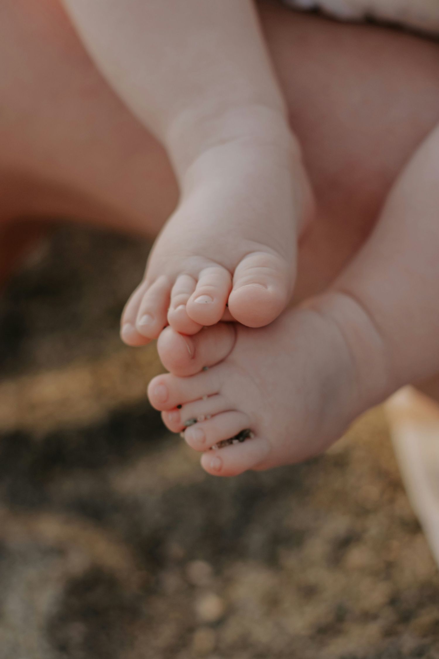 Close-up of chubby newborn baby feet with tiny toes outdoors.