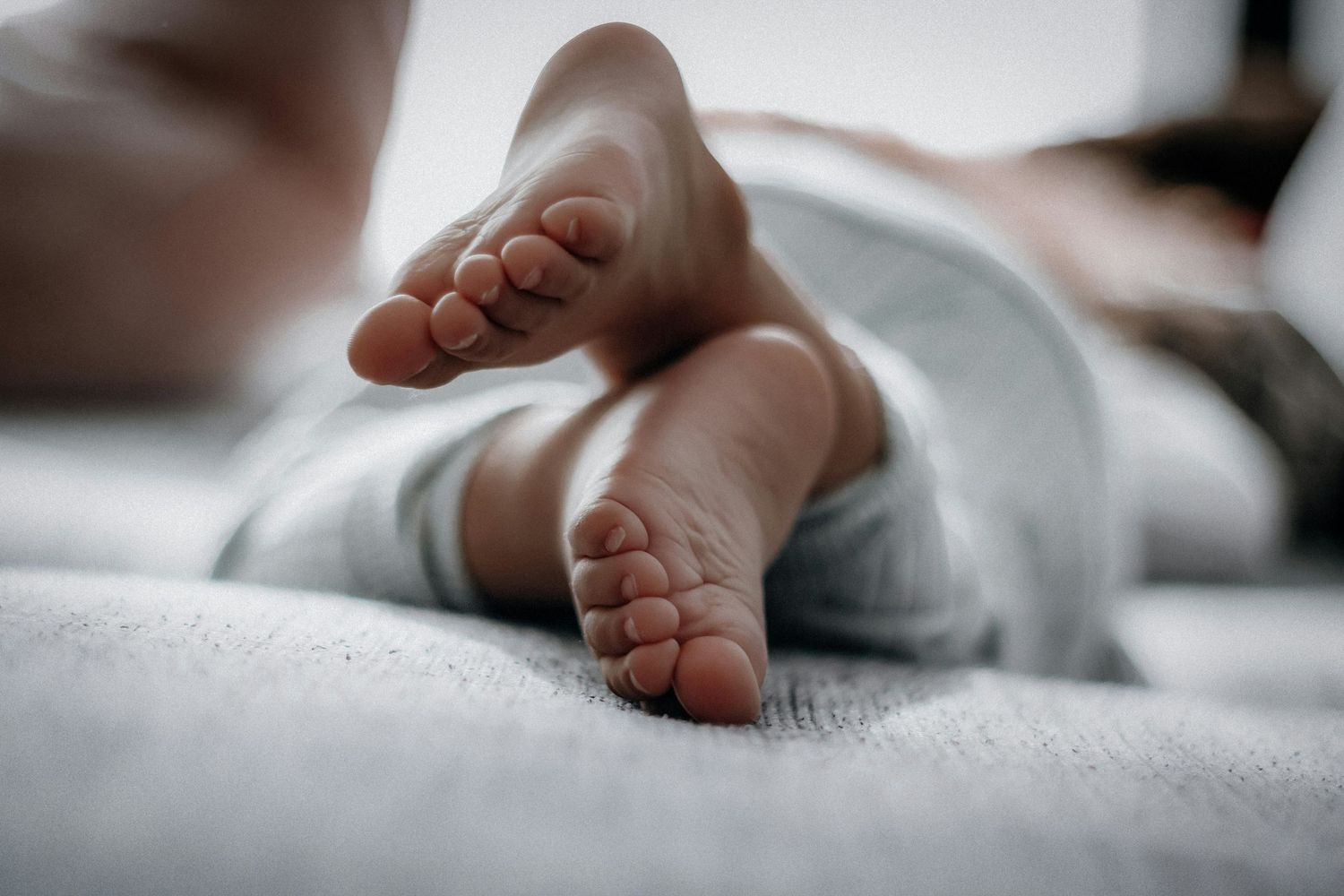 Close-up of tiny newborn baby feet resting on soft white blanket.