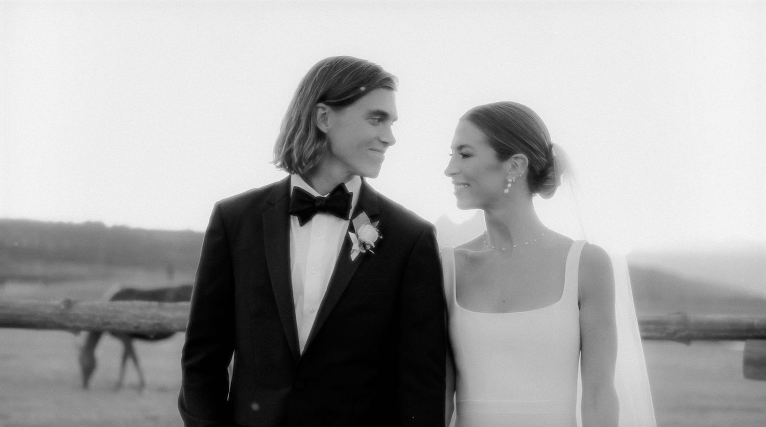 A black and white photo of a bride and groom sharing a tender moment outdoors on their wedding day.