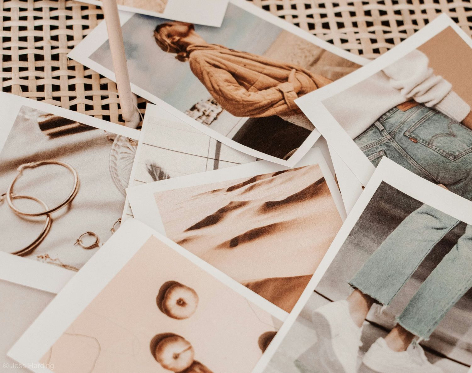 Collection of aesthetic fashion polaroid photos scattered on a wicker surface with gold jewelry.