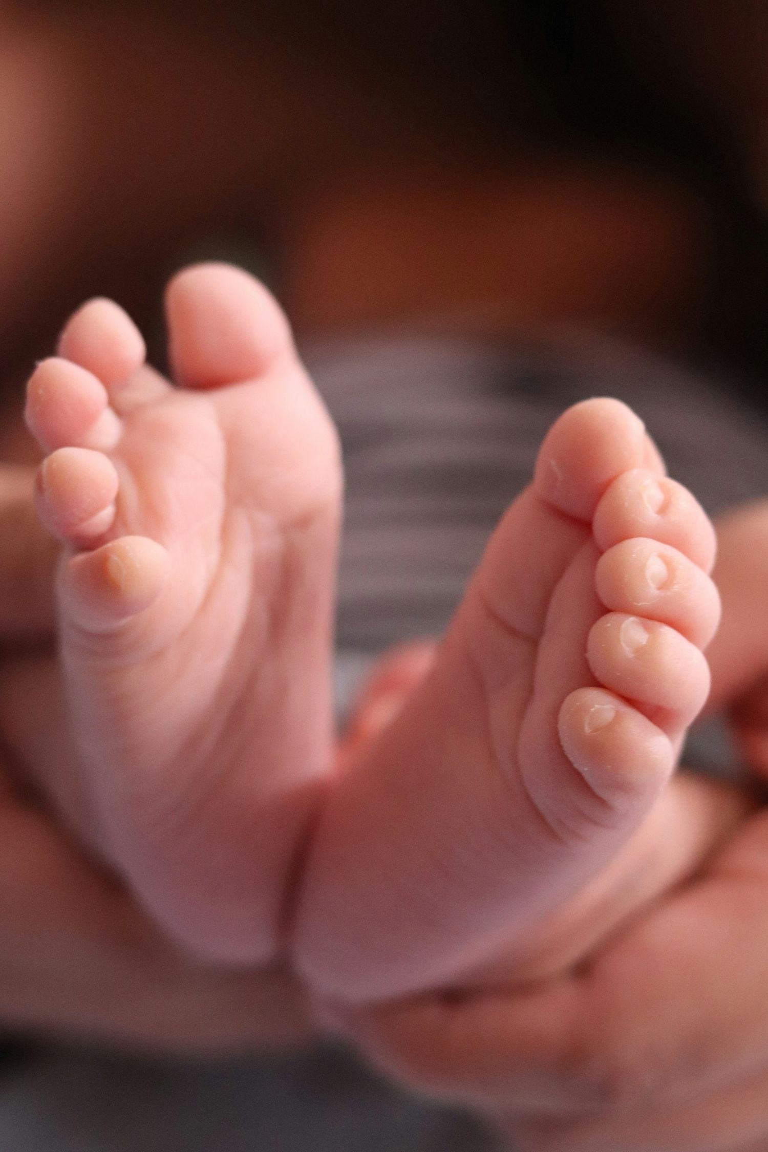 Tender close-up of two newborn baby feet with tiny delicate toes.