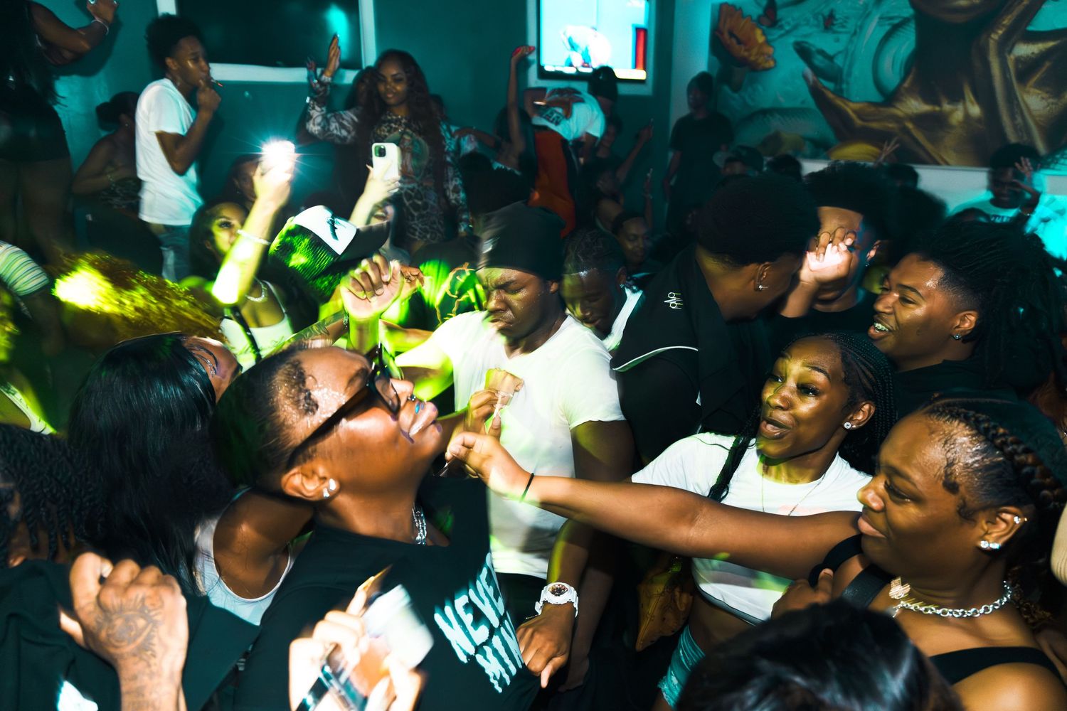 Energetic crowd dancing and celebrating at a vibrant nightclub party with colorful lighting.