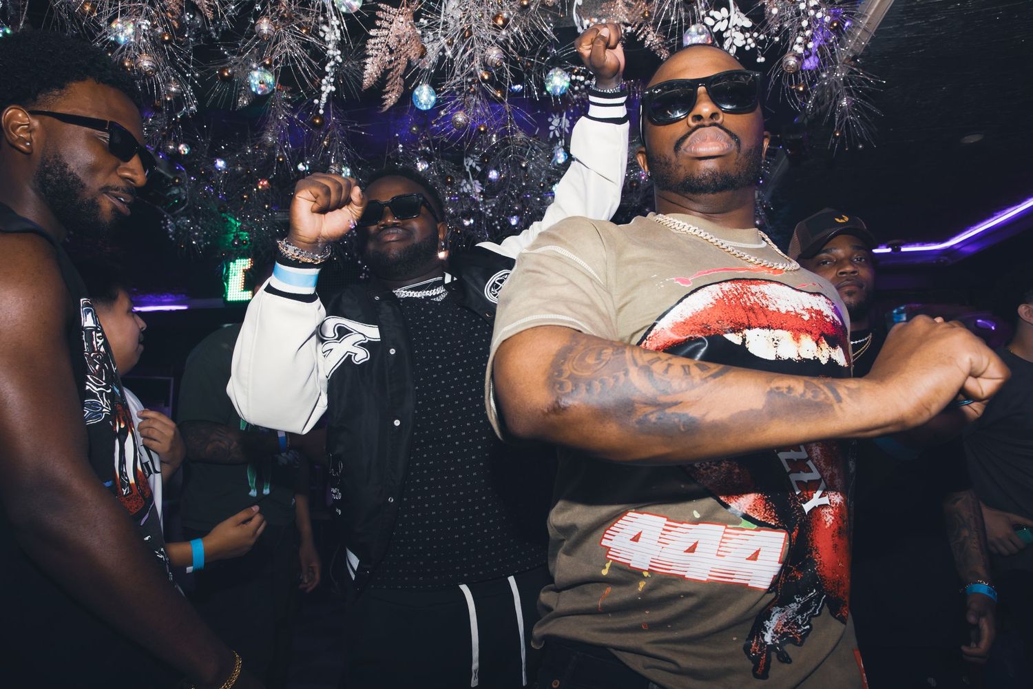 People dancing and celebrating at a nightclub party with festive decorations in the background.