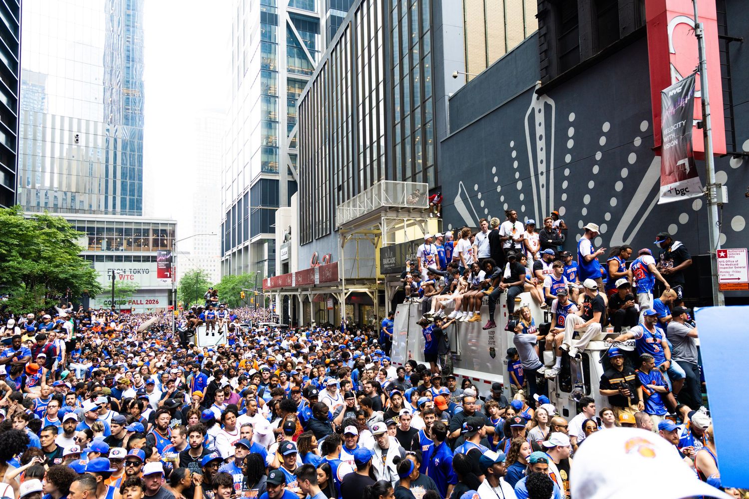 Massive crowd of fans in blue jerseys celebrating a championship parade on a packed city street.