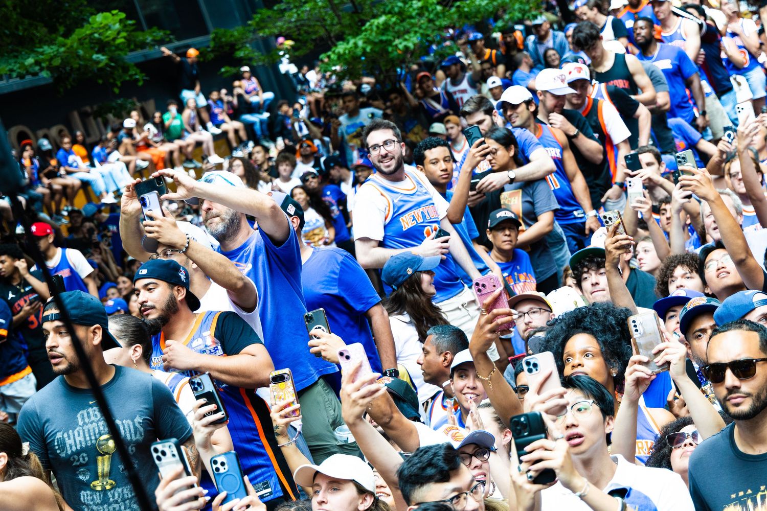 Large crowd of fans in blue shirts cheering and taking photos at an outdoor sports championship celebration event.