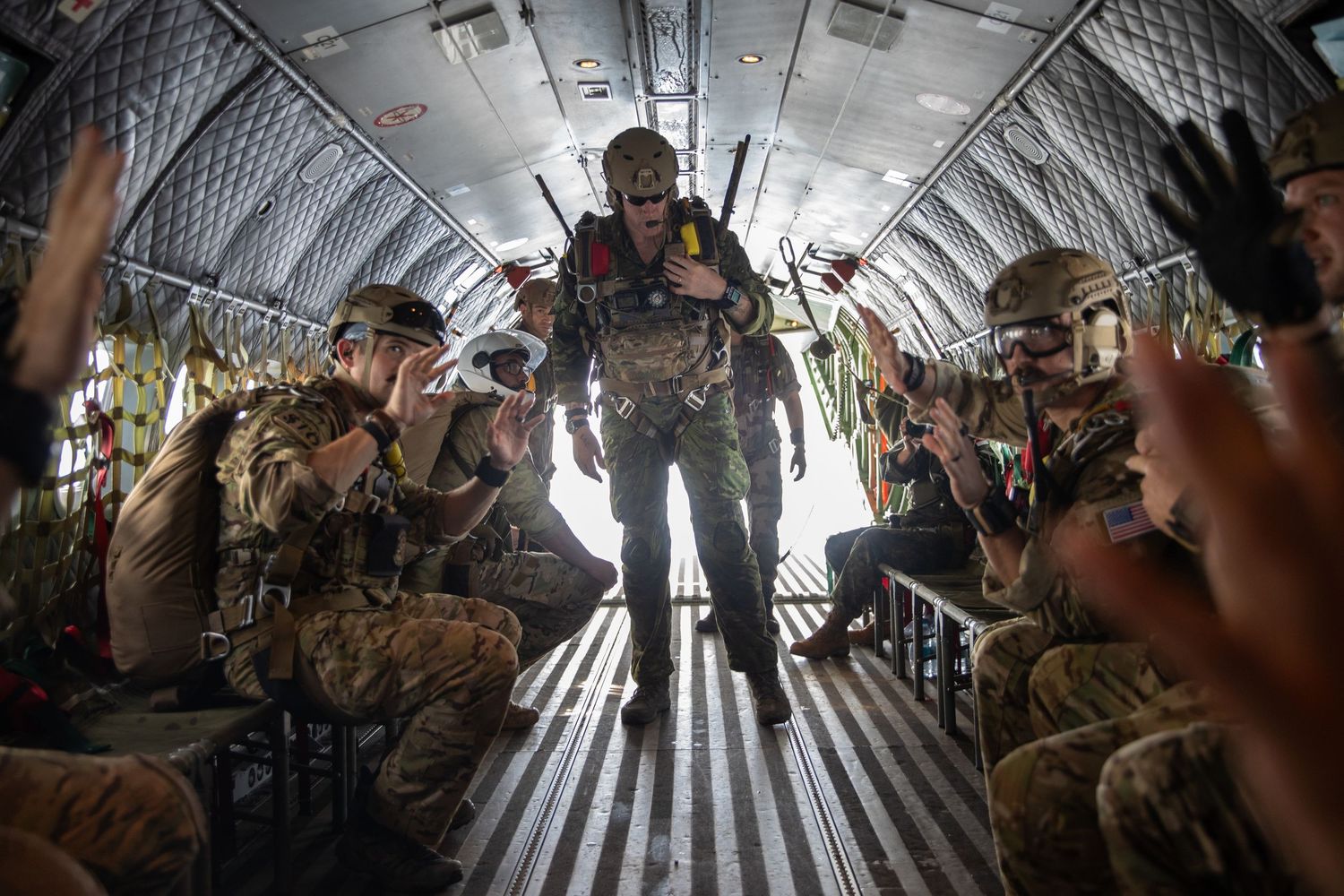A soldier walks through the aisle of a military aircraft as troops prepare for an airborne jump operation.