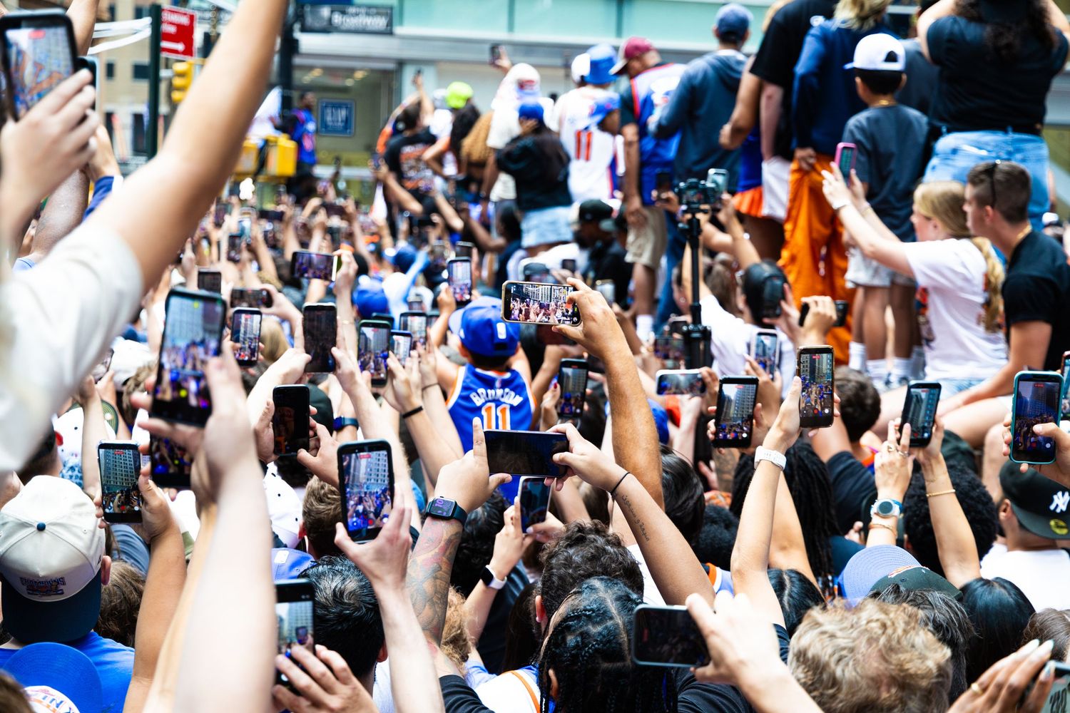 Large crowd of fans raising smartphones to photograph a celebrity appearance at a packed outdoor public event.