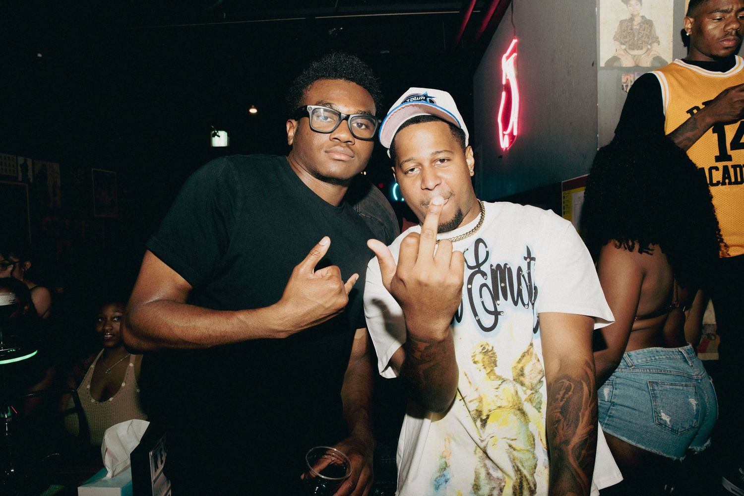 Two men smiling and posing together at a nightclub or bar event.