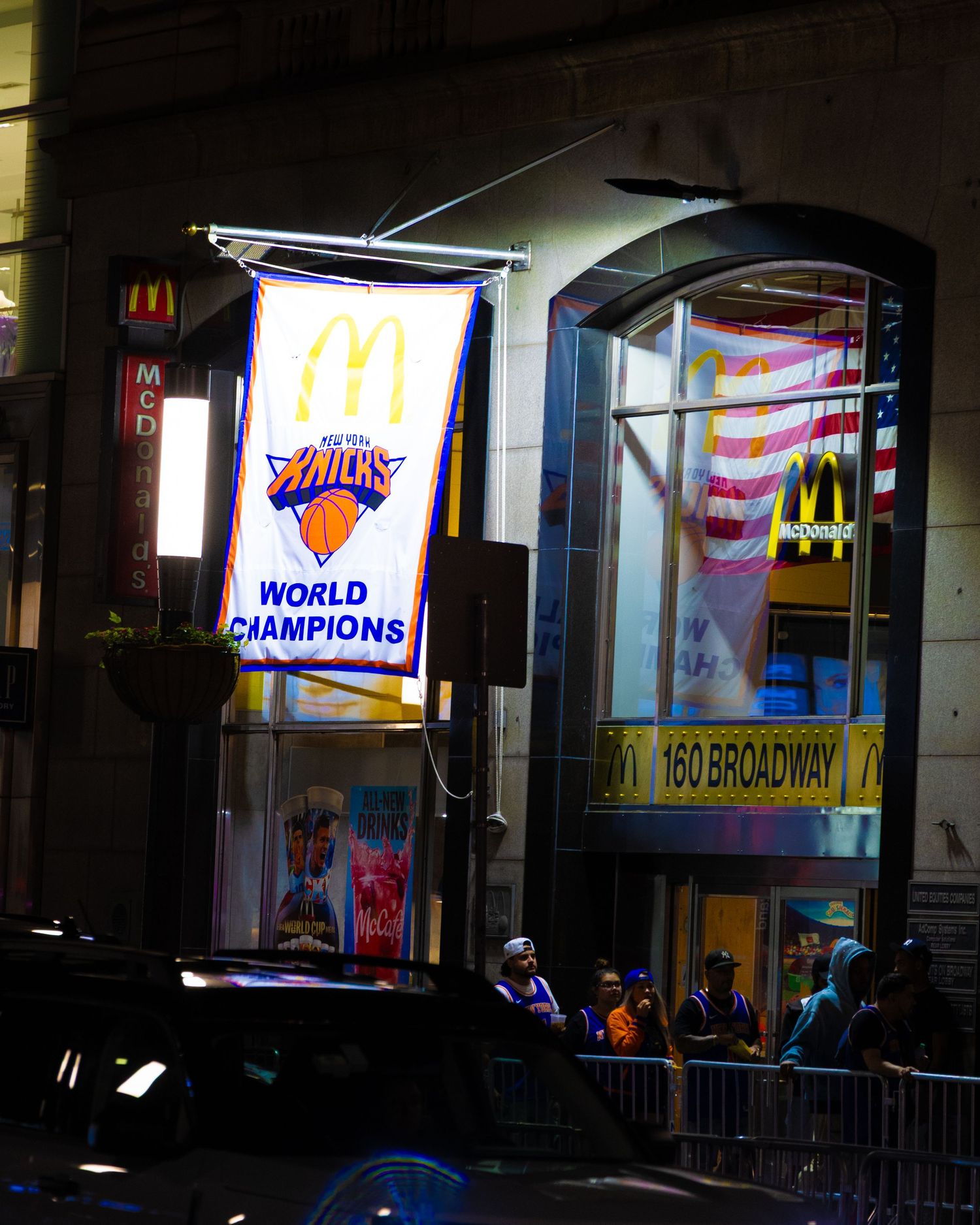 New York Knicks World Champions banner hanging outside a McDonald's at 160 Broadway in New York City at night.
