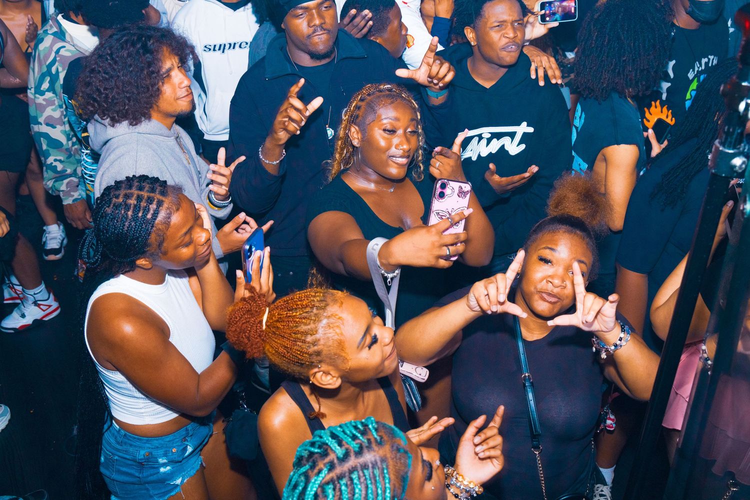 Group of friends dancing and posing at a lively nightclub party, wearing casual black outfits.