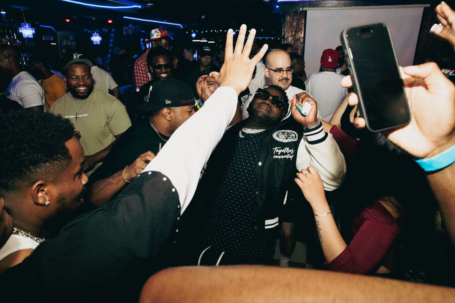 Crowd of partygoers celebrating together at a packed nightclub event.