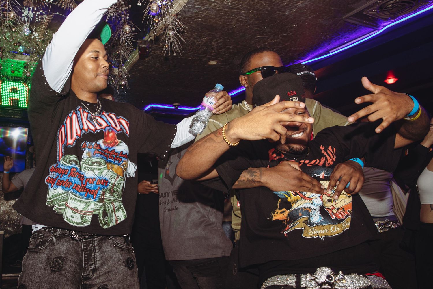 Two people toasting drinks together at a nightclub celebration under colorful lights.