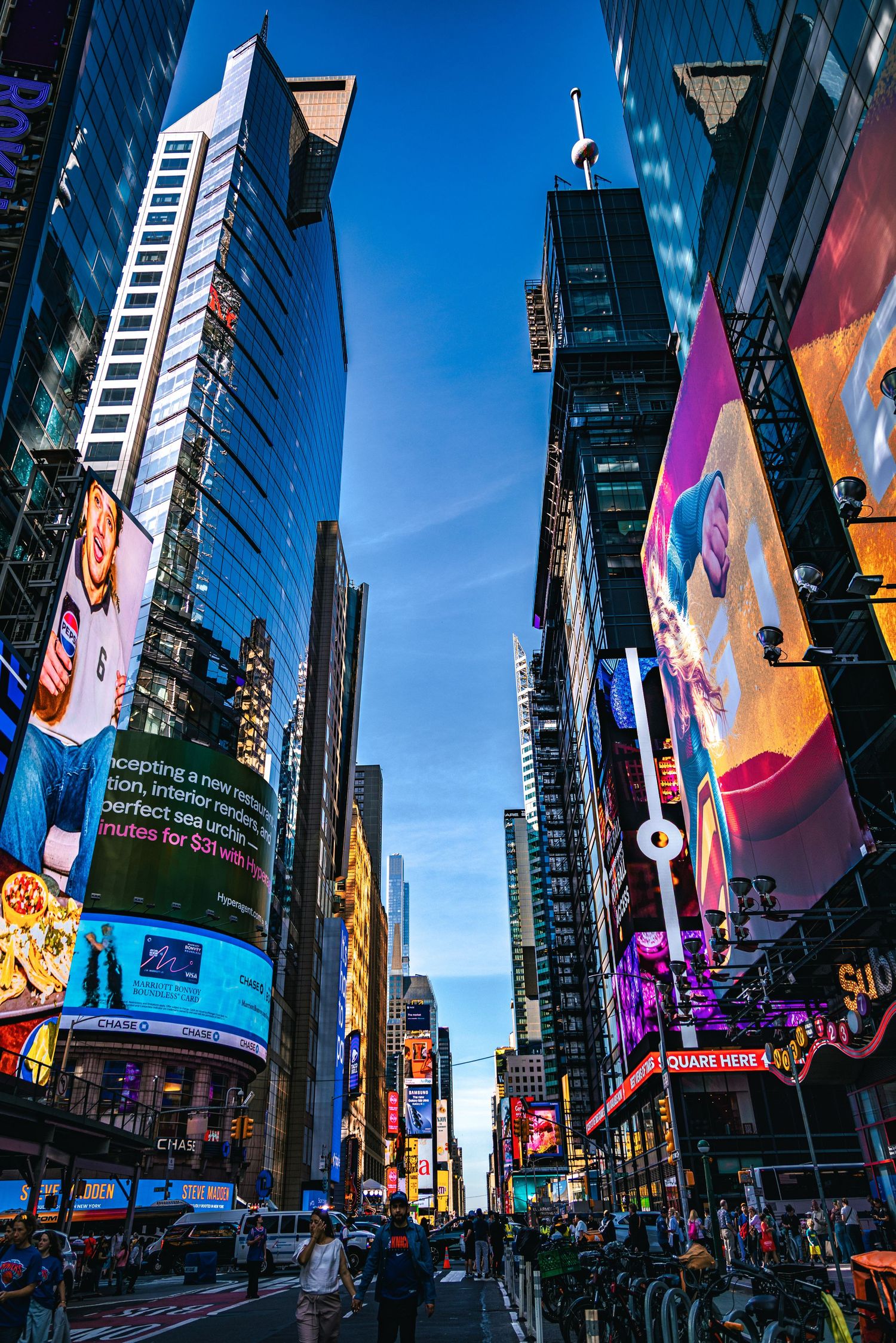Vibrant Times Square NYC at dusk with glowing billboards, skyscrapers, and busy streets filled with pedestrians.