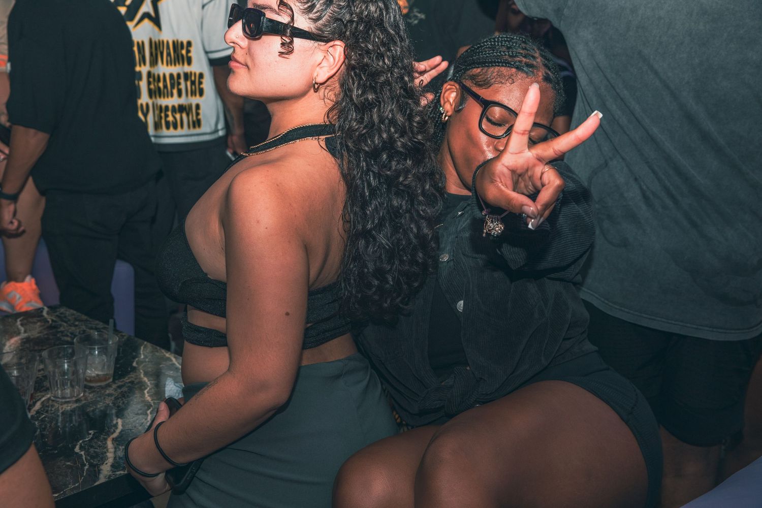 Two women dancing and posing together at a dark, energetic nightclub event.