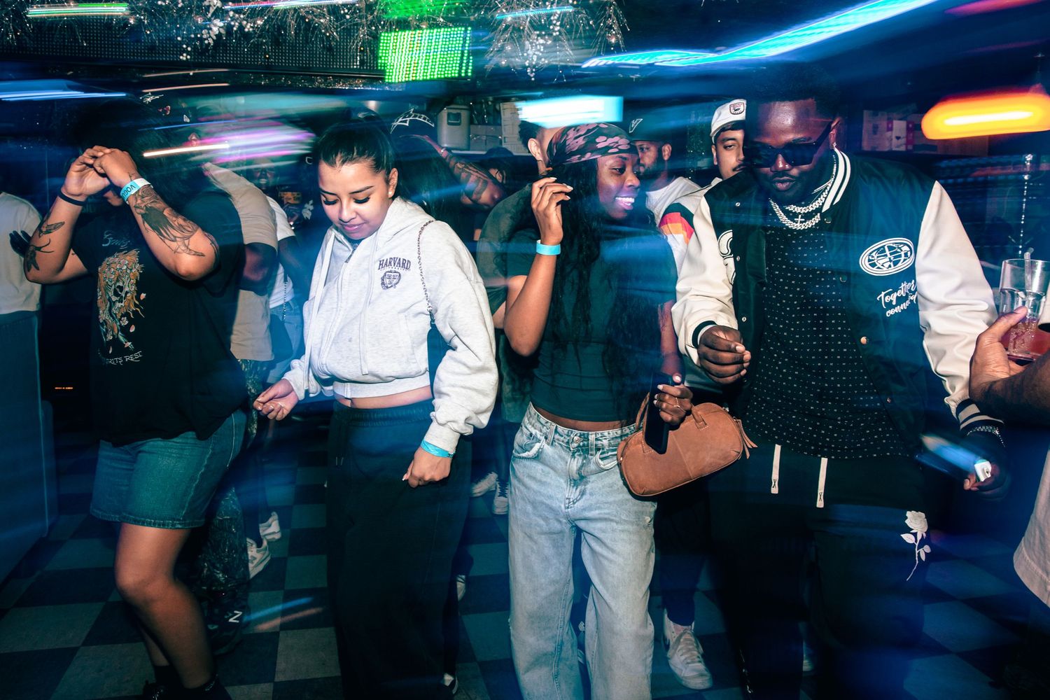 Friends dancing together under blue lights at an energetic indoor nightclub party.