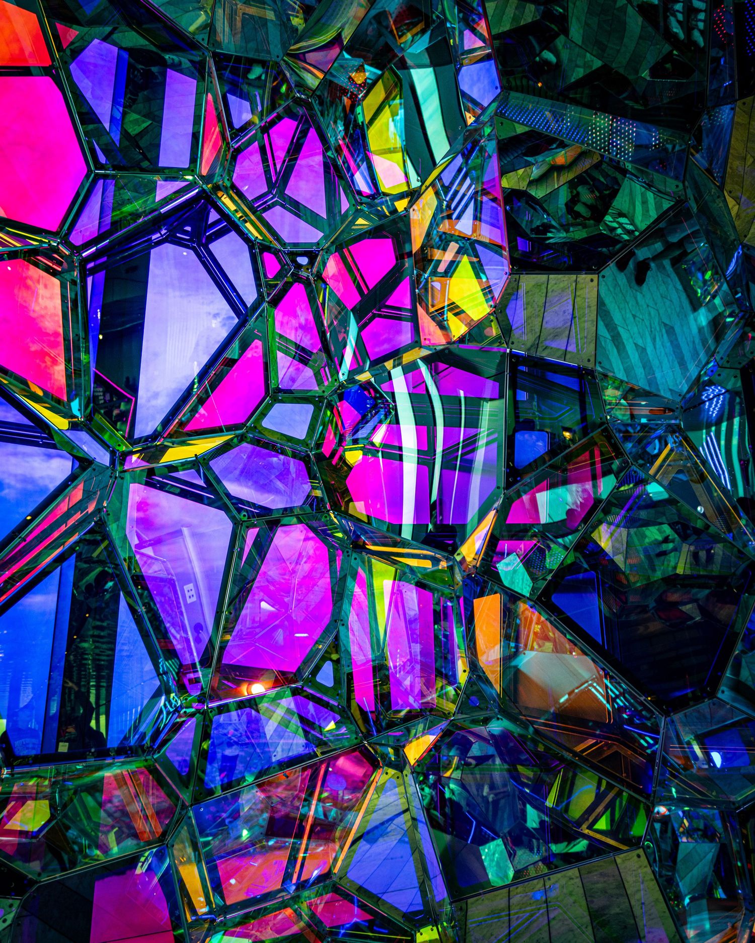 Abstract kaleidoscopic art installation with vibrant geometric panels in pink, blue, yellow, and green colors.