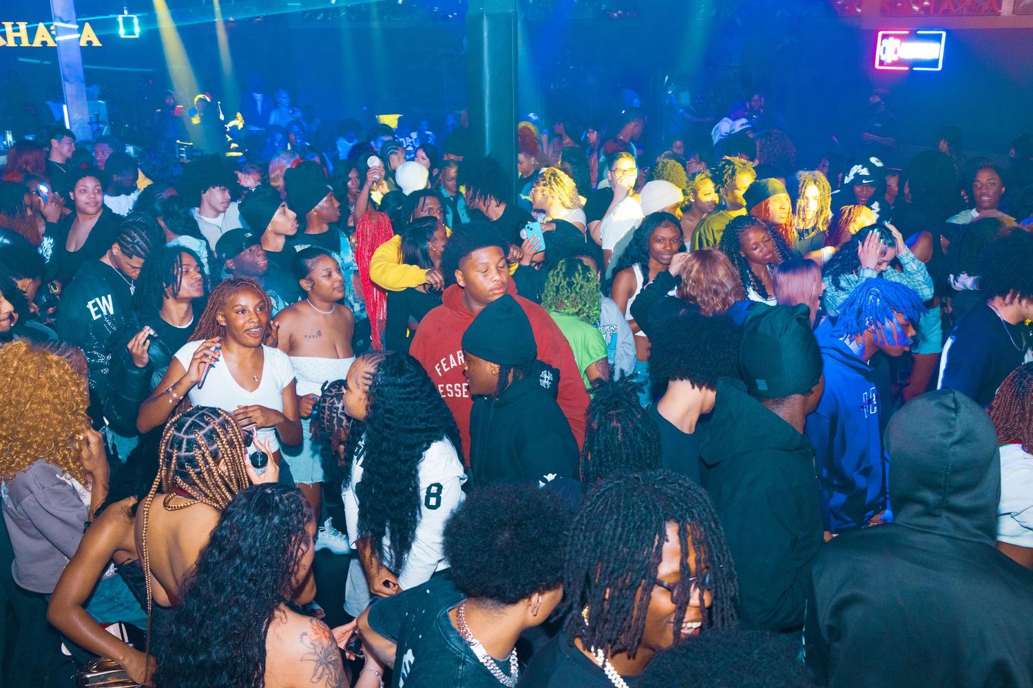 Large diverse crowd enjoying a lively nightclub party under colorful lights at Sahara bar.