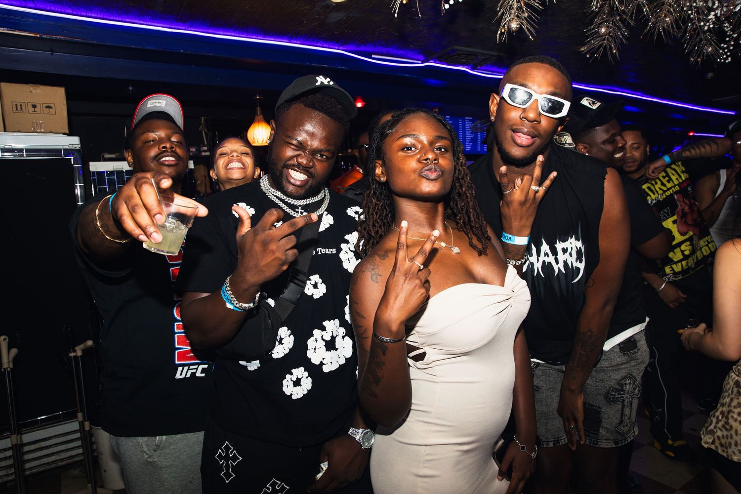Group of young people posing and smiling together at a vibrant nightclub party.